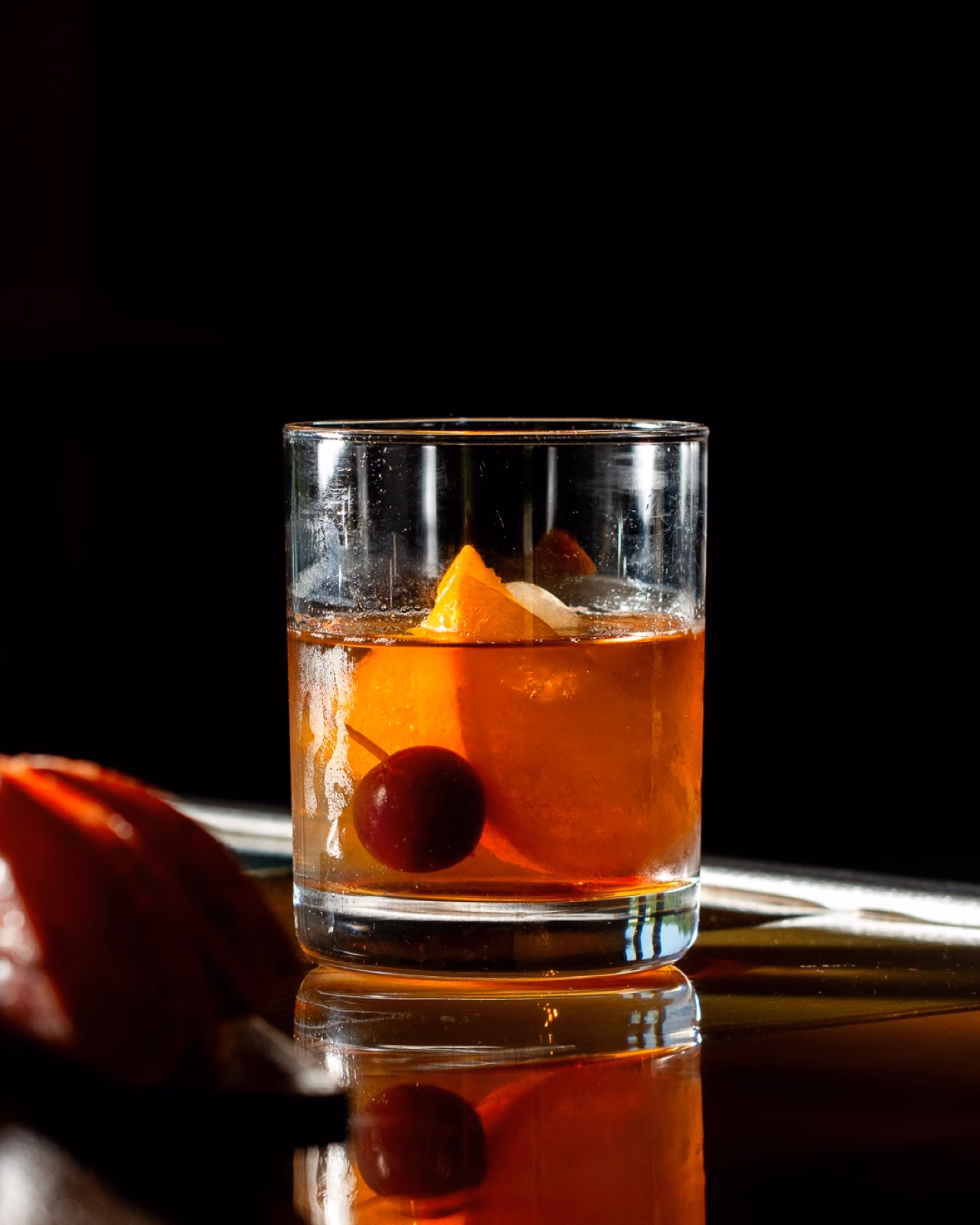 An amber cocktail glowing against a black background