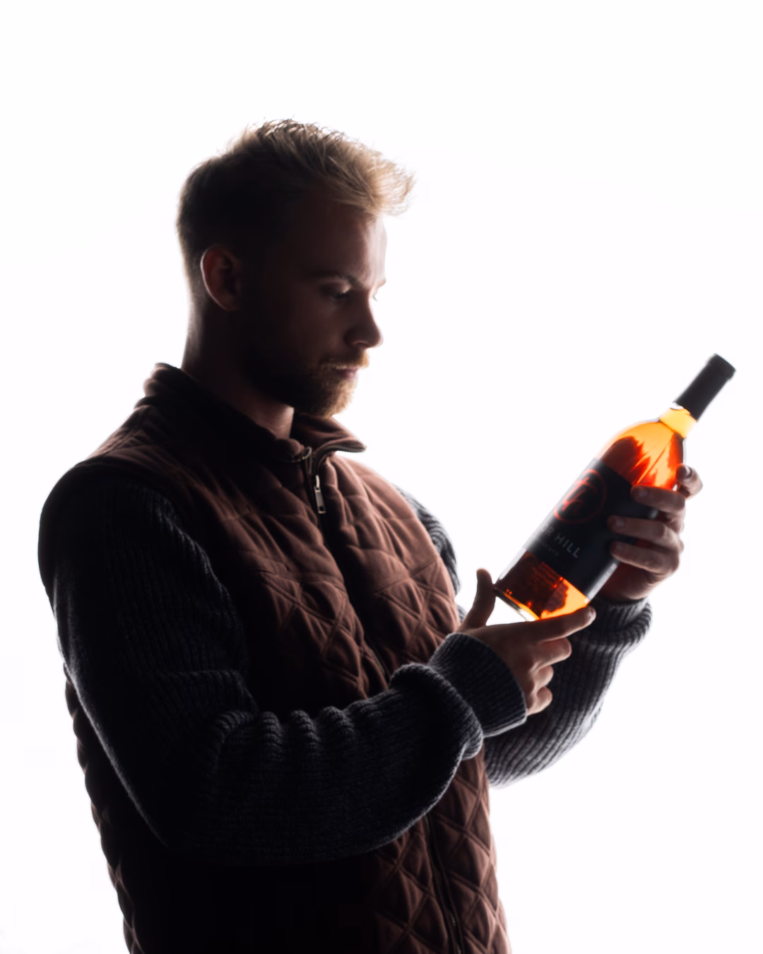 Oscar Cramer holding a Tabor Hill wine bottle in the studio