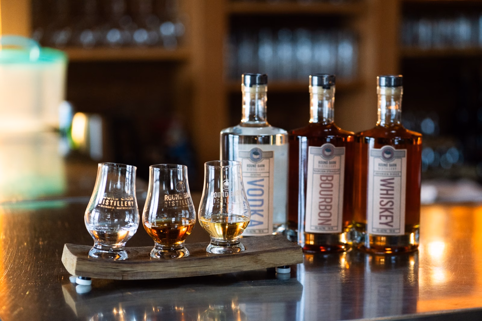 A tasting flight and three spirits bottles glowing at the bar